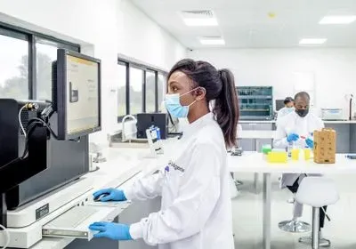 Women looks at computer screen in a lab coat and mask